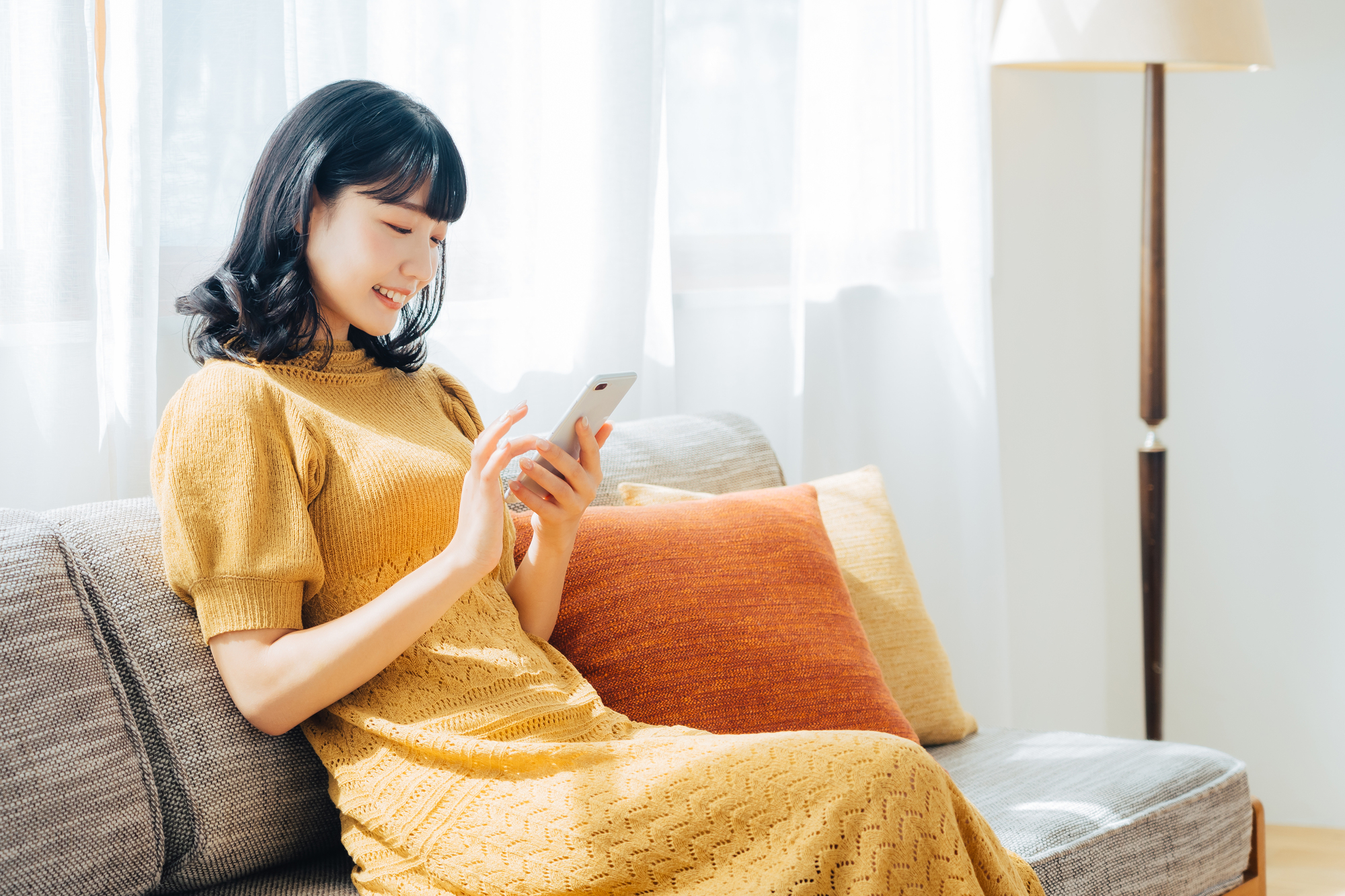 自宅のデスクでPCを使い、笑顔で制作を進めている30代の女性